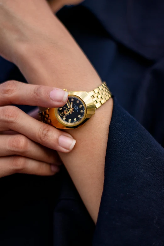 a close up of a person wearing a watch, by Julia Pishtar, gold and black blu, ripley scott, omega, gold plated