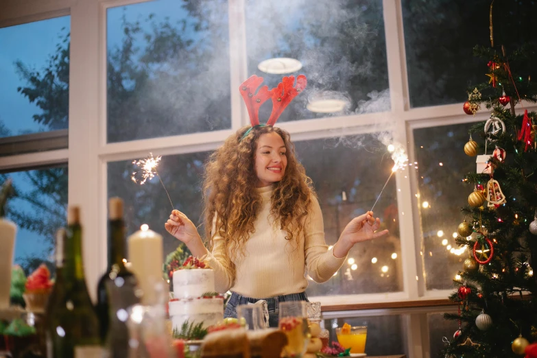 a woman standing in front of a christmas tree holding sparklers, a picture, by Julia Pishtar, pexels contest winner, happening, in a kitchen, with long curly hair, party hats, avatar image