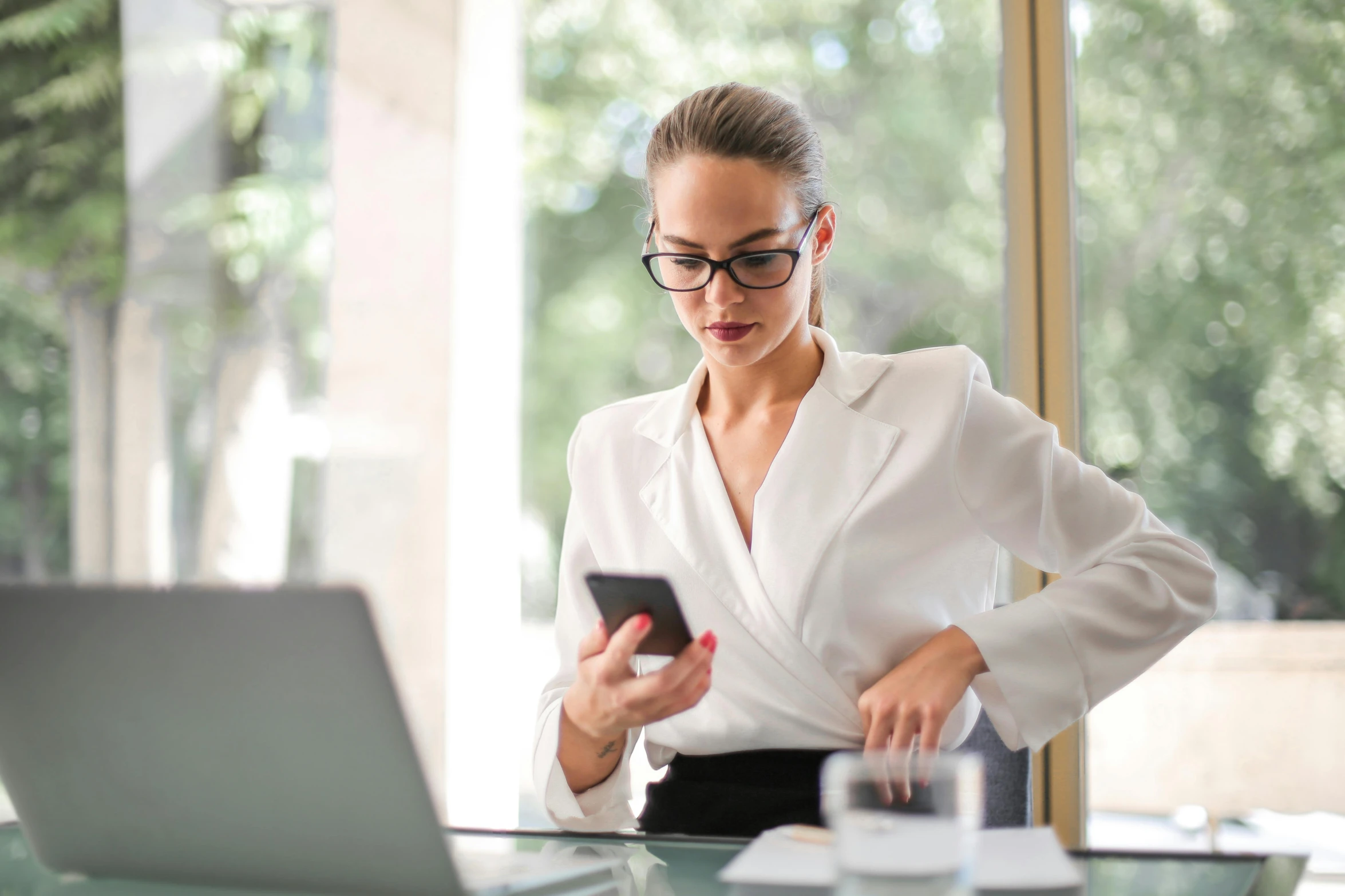 a woman in a white shirt is looking at her cell phone, pexels, worksafe. instagram photo, librarian, laptop, wearing a suit and glasses