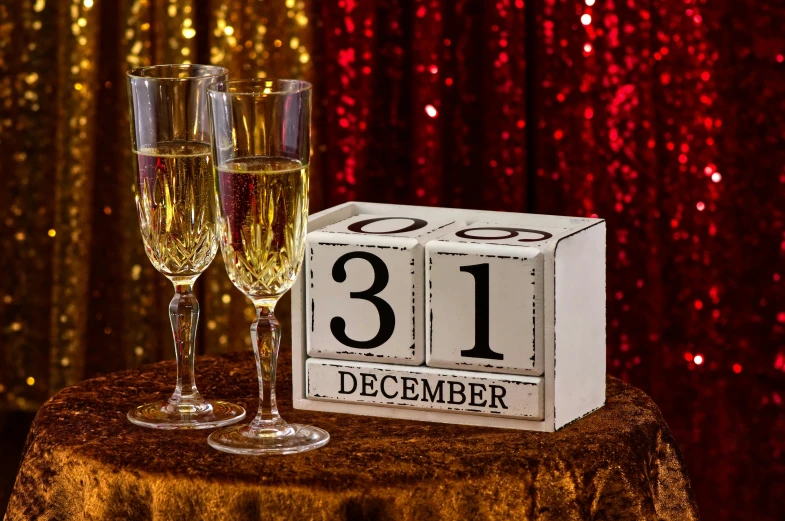 a couple of champagne glasses sitting on top of a table, a picture, by Meredith Dillman, shutterstock, happening, countdown, (1 as december, number 31!!!!!, small square glasses