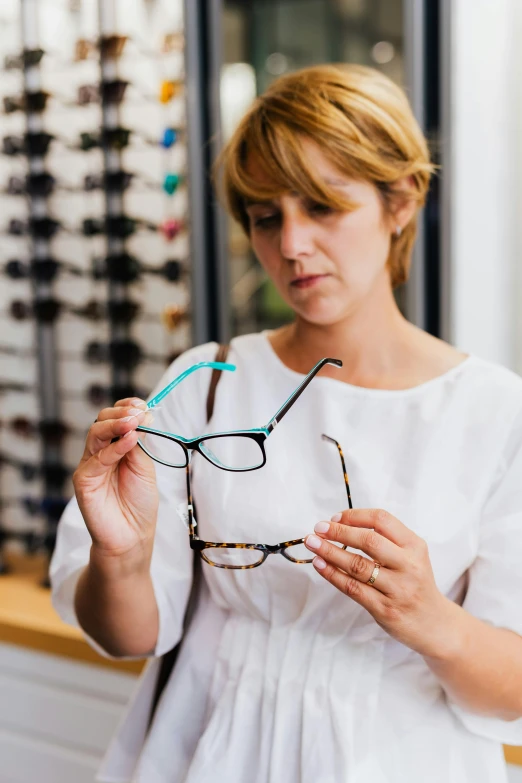 a woman holding a pair of glasses in her hands, inspect in inventory image, square rimmed glasses, split near the left, chromatic