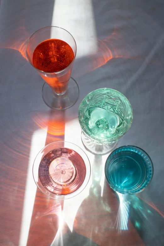 a group of glasses sitting on top of a table, inspired by Carlo Martini, summer light, celestial, pink and teal and orange, morning sunlight