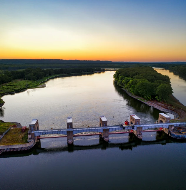 a large body of water with a bridge over it, by Adam Marczyński, pexels contest winner, happening, golden hour 8k, red river, drone footage, thumbnail