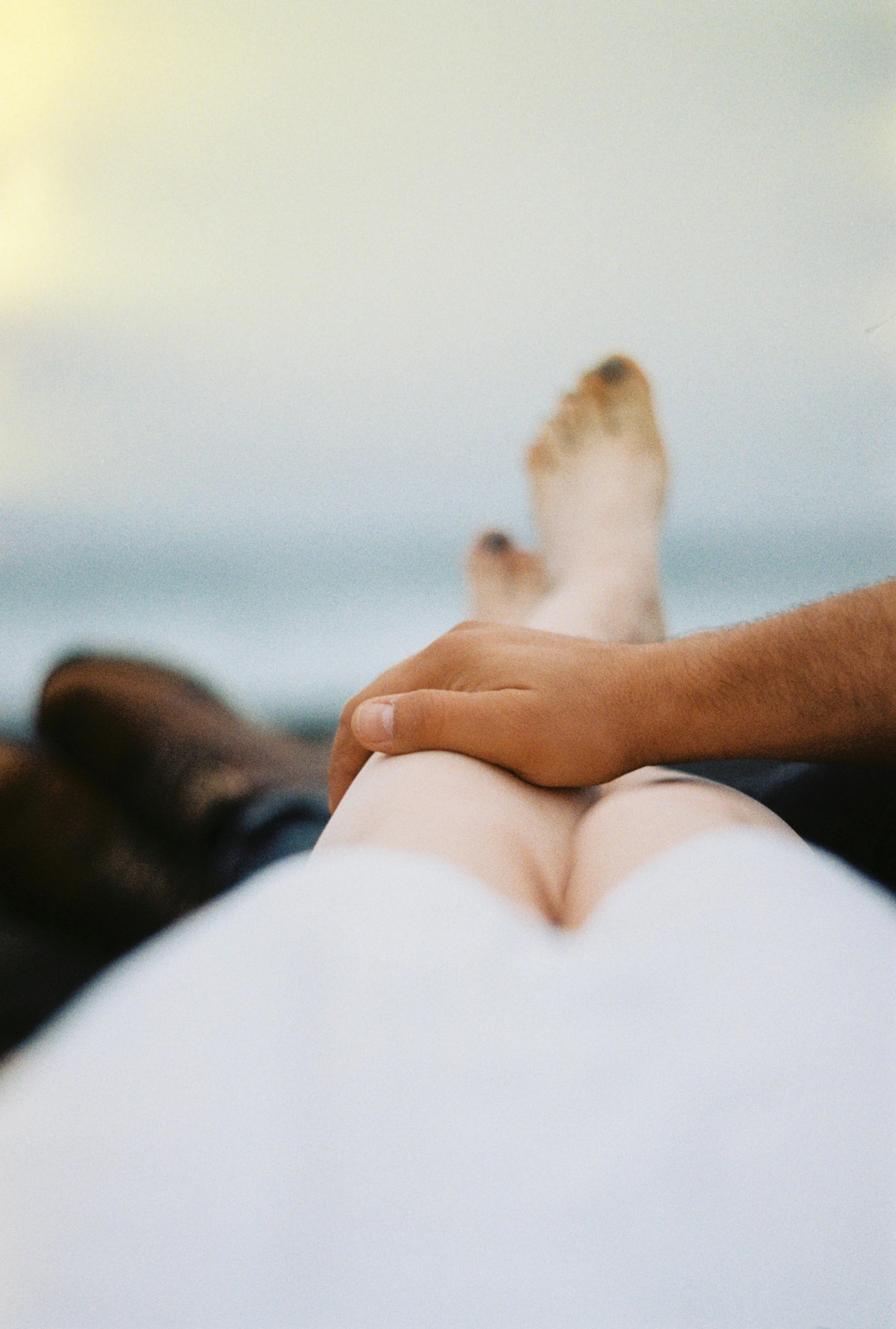 a person laying on a surfboard on the beach, unsplash, renaissance, holding hands, thighs close up, rooftop romantic, sitting