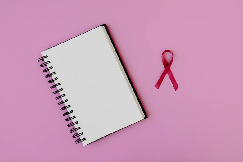 a notebook with a pink ribbon next to it, trending on pexels, full body image, thumbnail, background image, tumours