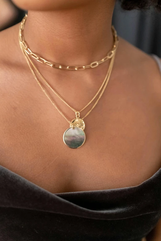 a close up of a woman wearing a necklace, an album cover, inspired by Perle Fine, labradorite, gold medal, abalone, moonlight grey