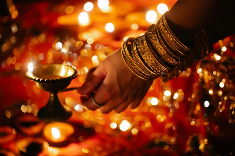 a woman holding a lit oil lamp in her hand, trending on unsplash, hurufiyya, brass bracelets, wearing festive clothing, thumbnail, submerged temple ritual scene