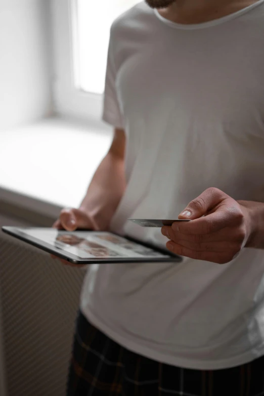 a man standing in front of a window holding a tablet computer, a picture, pexels contest winner, holding ace card, holding knife, close up to the screen, reading