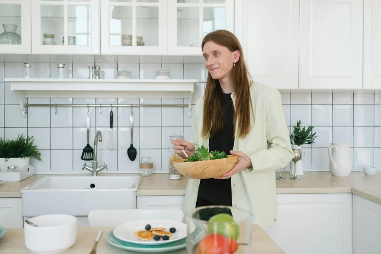 a woman standing in a kitchen holding a bowl of food, inspired by Louisa Matthíasdóttir, pexels contest winner, on a white table, profile image, serving suggestion, tv show still