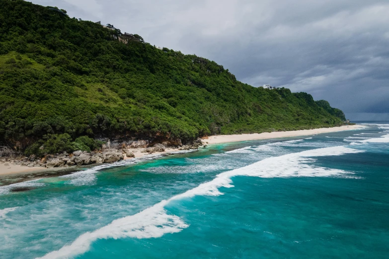 a large body of water next to a lush green hillside, an album cover, by Peter Churcher, pexels contest winner, australian beach, monsoon on tropical island, beach on the outer rim, conde nast traveler photo