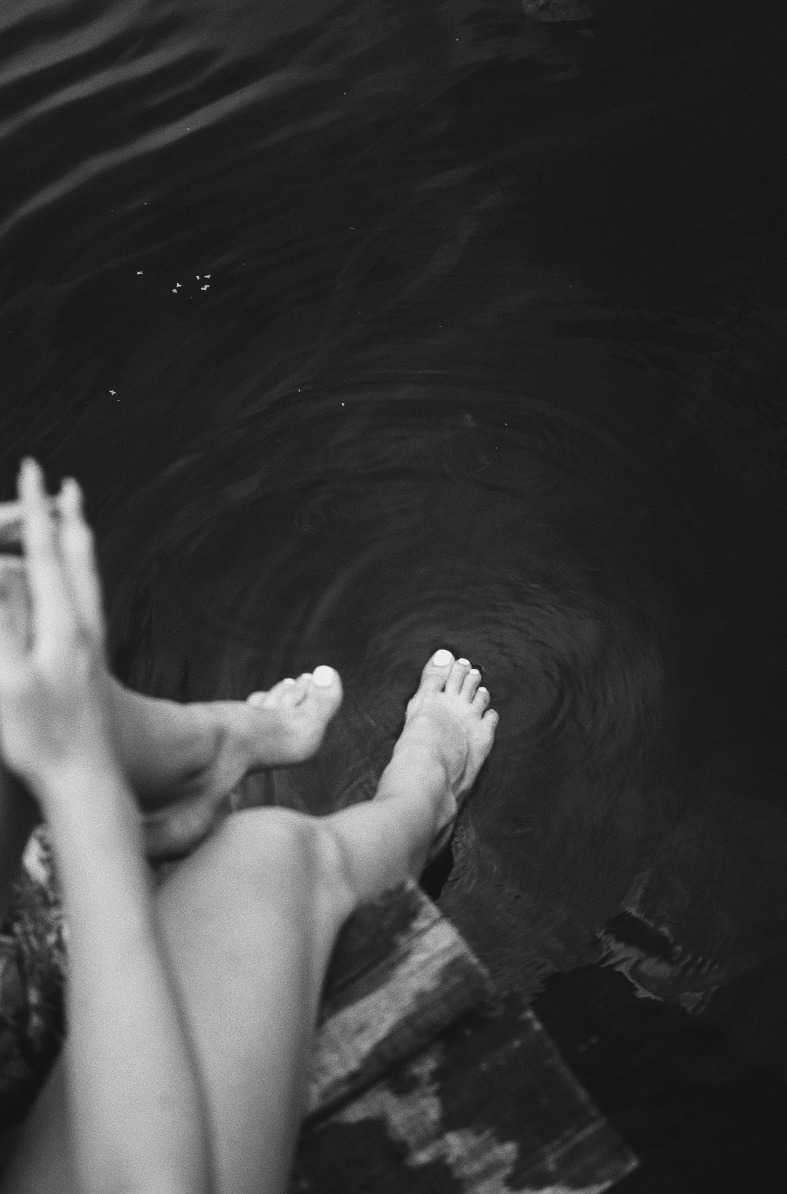 a person sitting in the water with their feet in the water, a black and white photo, unsplash, aestheticism, ✨🕌🌙, show from below, childhood friend vibes, female floating