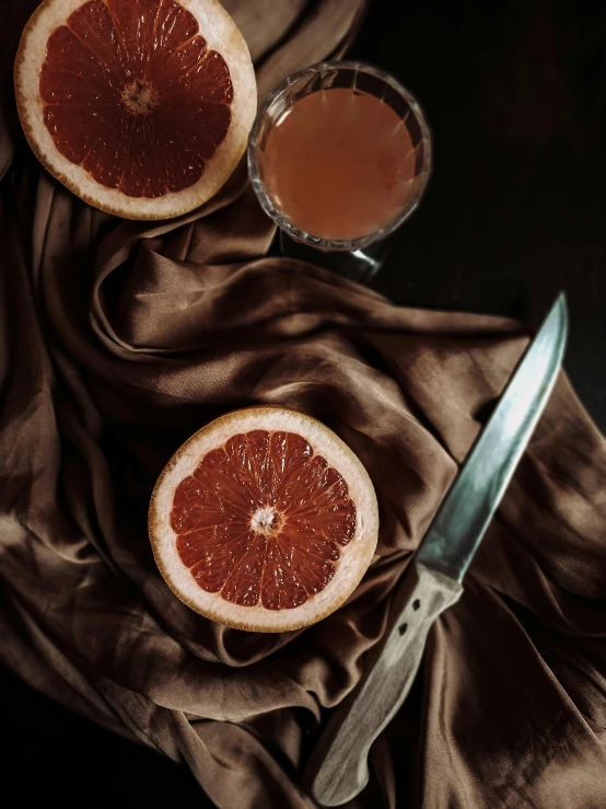 two grapefruits and a knife on a cloth, trending on unsplash, renaissance, 💋 💄 👠 👗, sitting on a mocha-colored table, alessio albi, juice