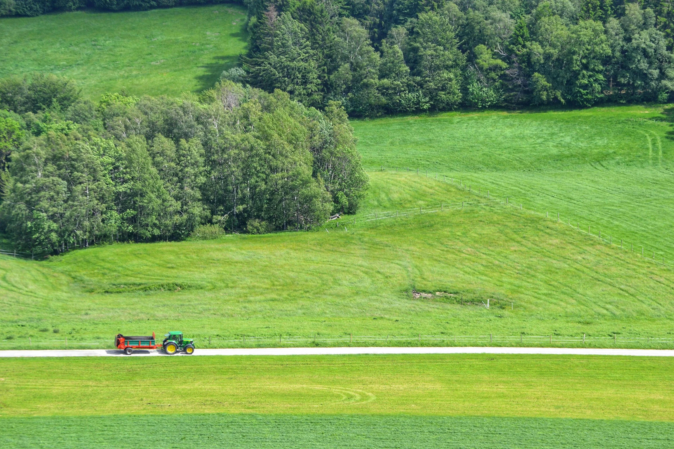 a tractor driving down a road through a lush green field, by Anato Finnstark, pexels contest winner, folk art, switzerland, 2 5 6 x 2 5 6 pixels, panoramic shot, people at work