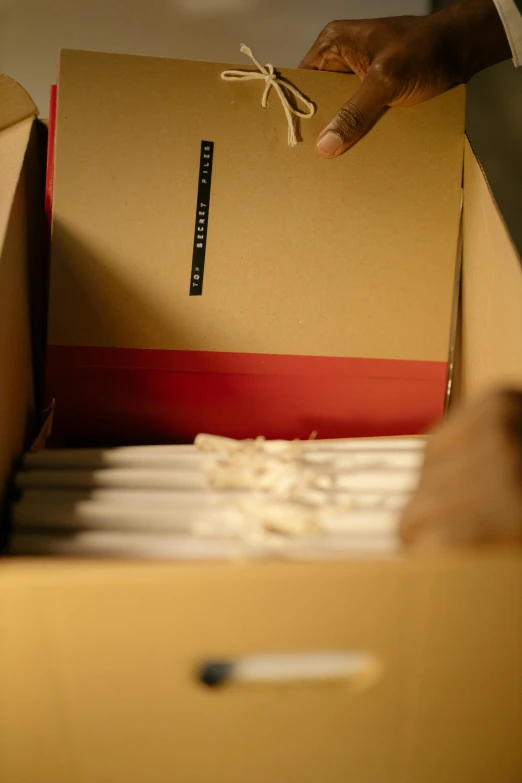 a close up of a person putting something in a box, an album cover, by David Simpson, process art, japanese collection product, streamlined spines, ecommerce photograph, parchment paper