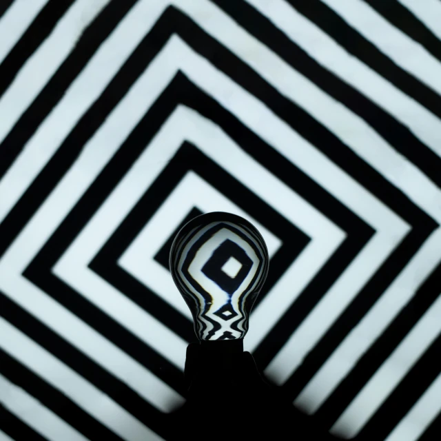 a light bulb sitting on top of a black and white floor, a microscopic photo, inspired by Alexander Rodchenko, flickr, optical illusion, op art with big bold patterns, square lines, stripe over eye, psychedelic black light