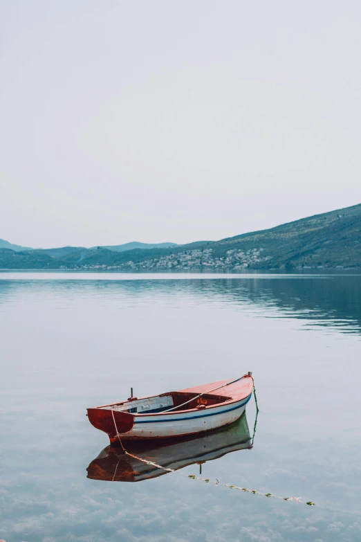 a red and white boat sitting on top of a lake, a picture, by Elsa Bleda, trending on unsplash, greece, grey, a wooden, conde nast traveler photo