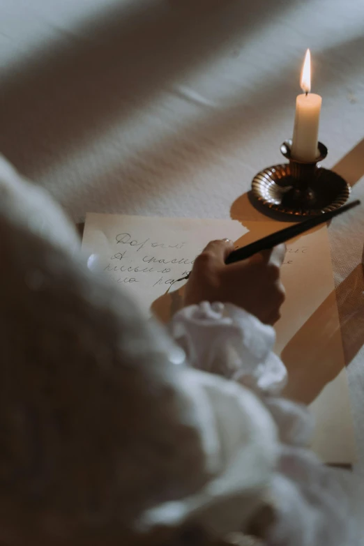 a person writing on a piece of paper next to a candle, by Daniel Seghers, unsplash contest winner, romanticism, regency-era, wedding, instagram story, hammershøi