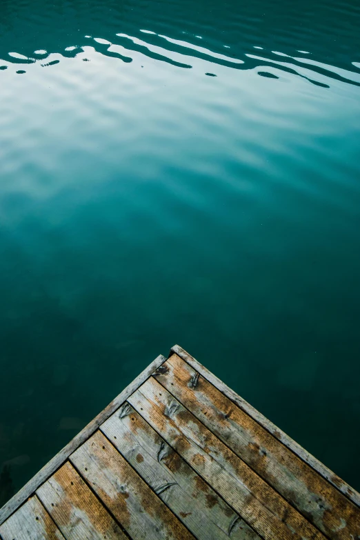 a dock in the middle of a body of water, a picture, by Sebastian Spreng, trending on unsplash, minimalism, teal paper, looking down on the camera, in muted colors, vertical