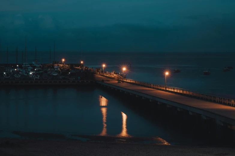 a pier next to a body of water at night, pexels contest winner, happening, slight overcast lighting, thumbnail, seaside, blue