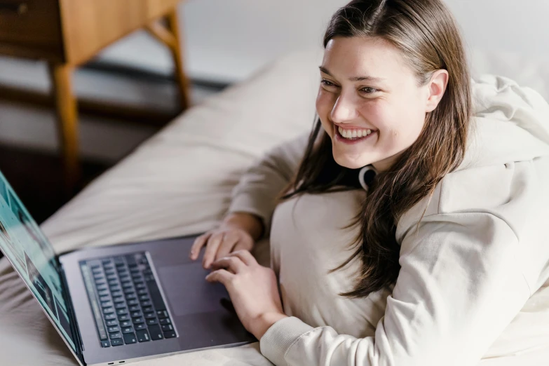a woman laying on a bed using a laptop computer, pexels contest winner, welcoming grin, lachlan bailey, profile image, woman with braided brown hair