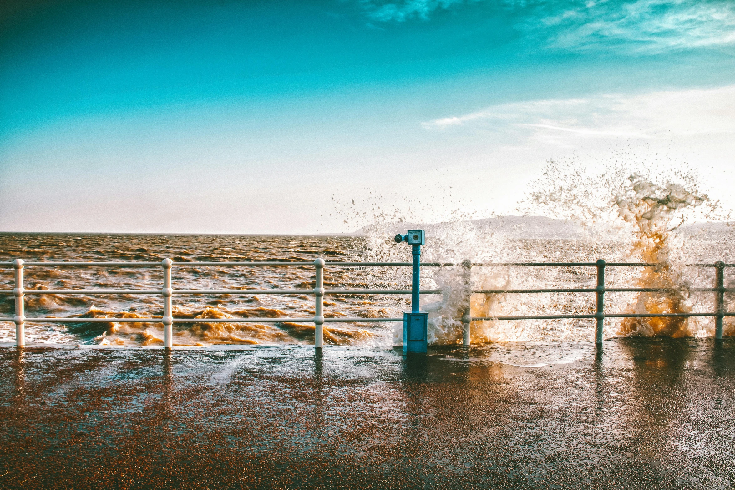 a man standing on top of a pier next to the ocean, a picture, unsplash, happening, there is water splash, maryport, thumbnail, high winds