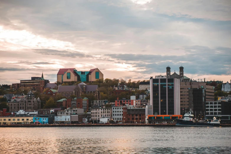 a large body of water with a city in the background, a photo, by Julia Pishtar, pexels contest winner, plein air, harbour, pink golden hour, quebec, norway