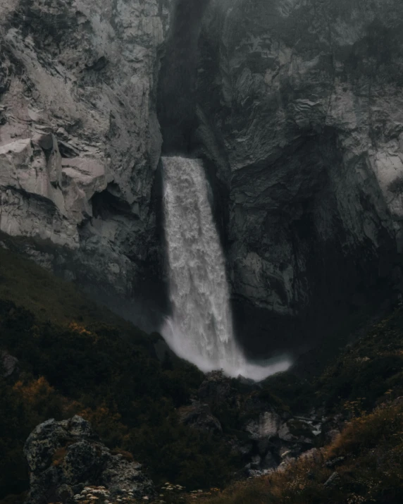 a waterfall in the mountains on a foggy day, an album cover, unsplash contest winner, naturalism, grey, overview, low quality photo, fall season