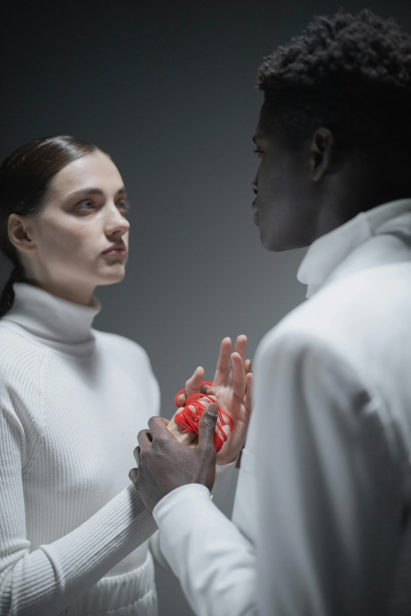 a woman standing next to a man holding a heart, a hologram, inspired by Anna Füssli, pexels contest winner, hyperrealism, adut akech, in white turtleneck shirt, dark people discussing, nonbinary model