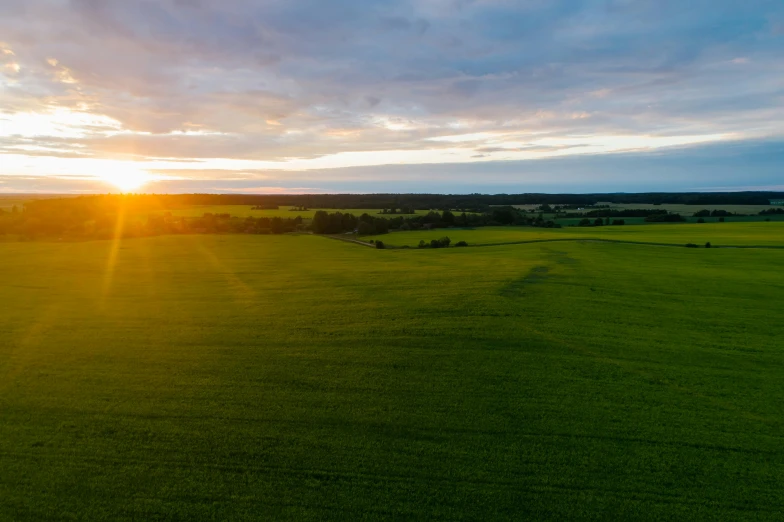 the sun is setting over a green field, by Thomas Häfner, pexels contest winner, wide high angle view, low ultrawide shot, detailed high resolution, mid morning lighting