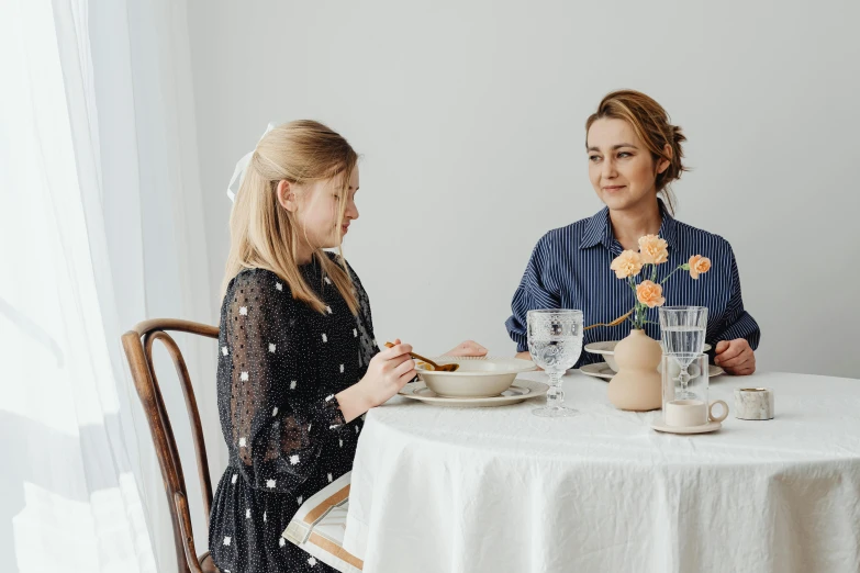 two women sitting at a table with plates of food, a portrait, by Alice Mason, pexels contest winner, white bg, daughter, emma watson sitting in chair, sydney sweeney