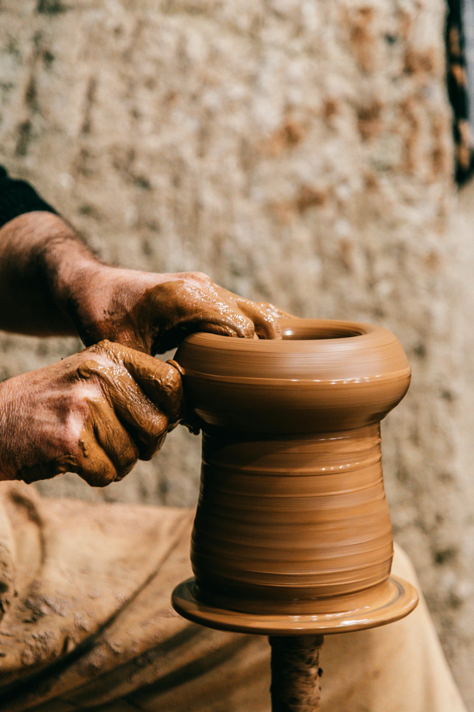 a man is making a clay pot on a potter's wheel, an abstract sculpture, trending on unsplash, oman, instagram story, brown, tall