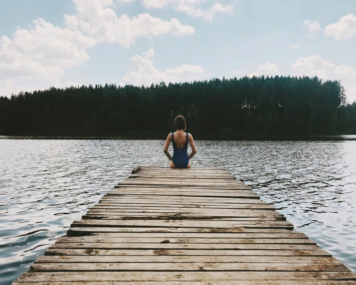 a person sitting on a dock near a body of water, swimming, {perfect body}, instagram post, walking away