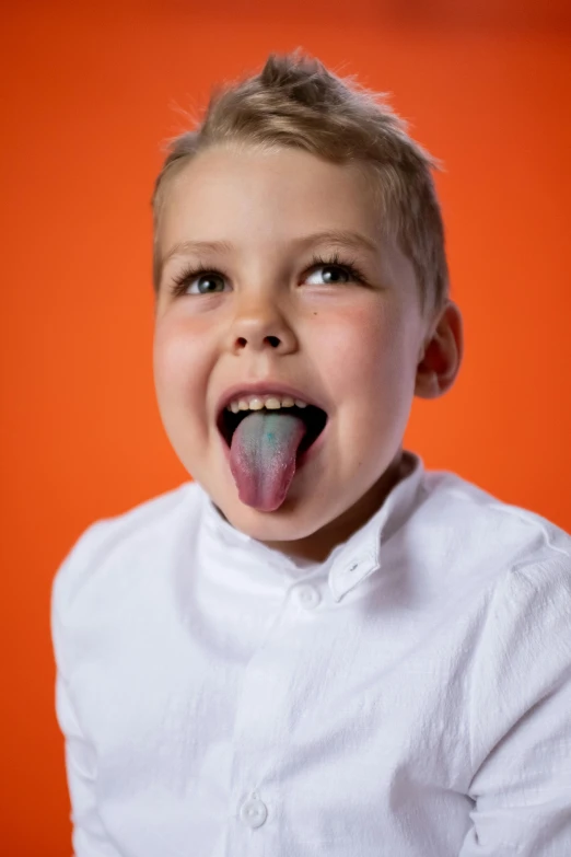 a young boy sticking his tongue out in front of an orange background, by Doug Ohlson, pexels contest winner, made of cotton candy, on grey background, orange and cyan paint decals, non binary model