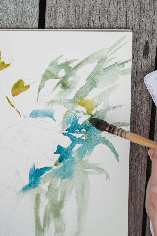 a close up of a person holding a paint brush, a watercolor painting, inspired by Wu Changshuo, botanicals, prussian blue and azo yellow, pencil and watercolour, painting a canvas