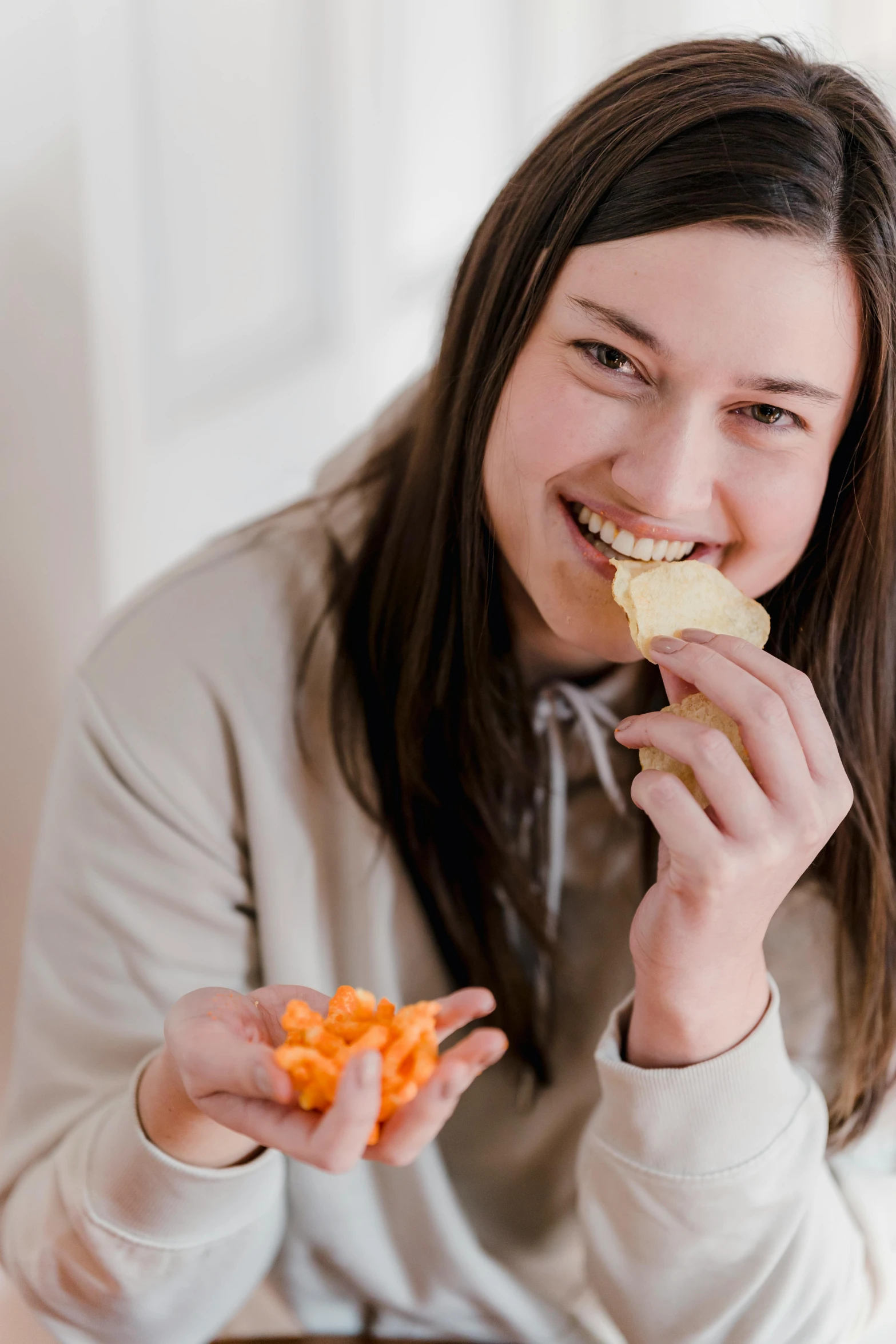 a woman sitting at a table eating a piece of food, orange and white, chips, pokimane, cheddar