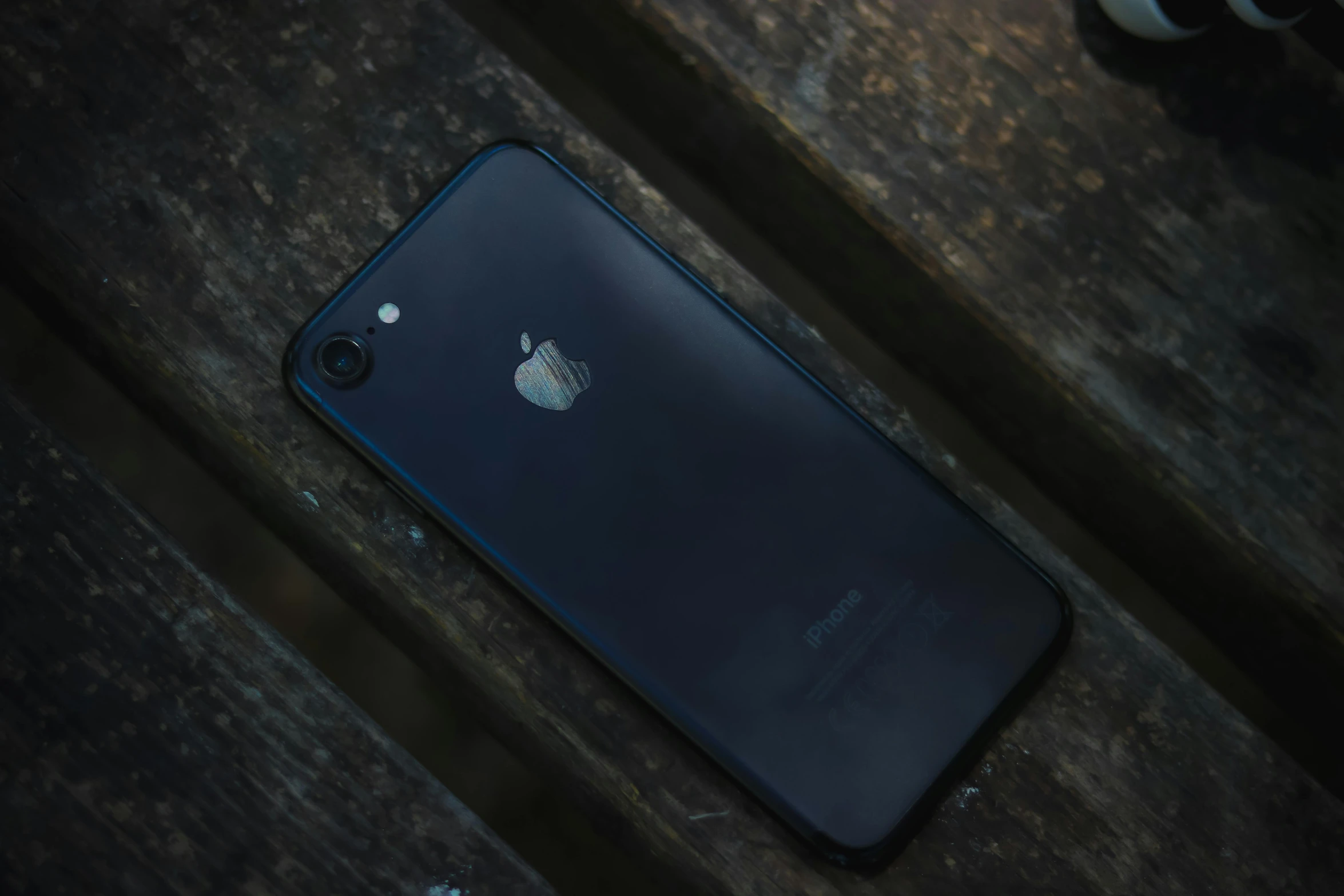 a black iphone sitting on top of a wooden table, pexels contest winner, square, low quality photo, trending photo, outdoor photo