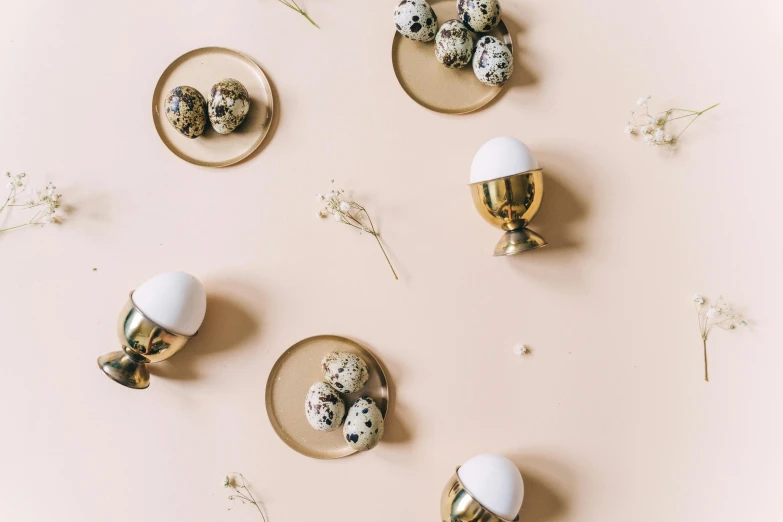 a bunch of eggs sitting on top of a plate, by Emma Andijewska, trending on unsplash, maximalism, metallic brass accessories, seamless pattern design, cups and balls, background image