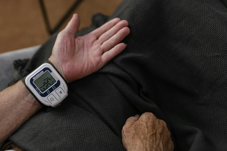 a close up of a person laying on a bed with a watch on their wrist, digital medical equipment, old man, profile image, ap press photo