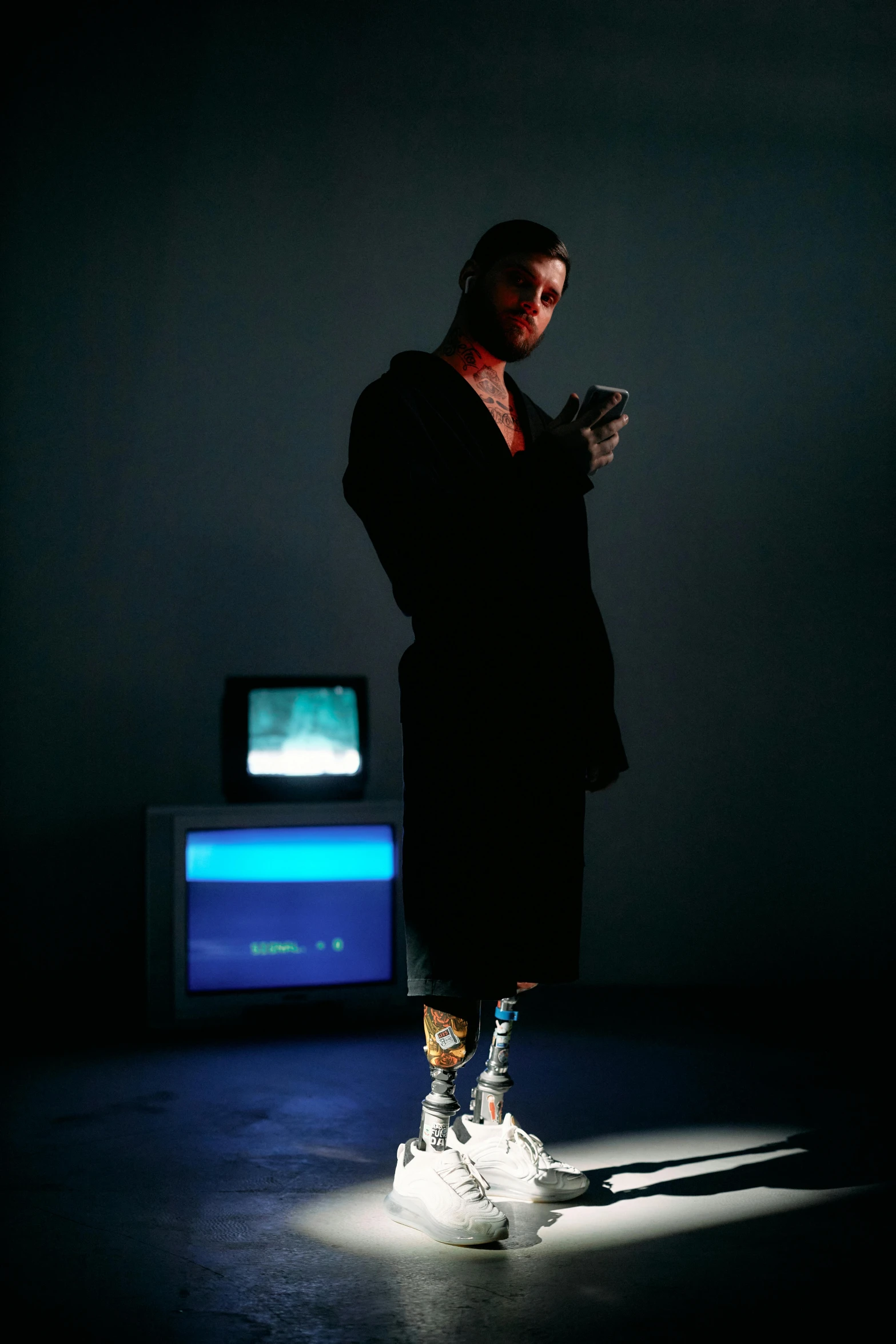 a man standing in front of a tv in a dark room, a hologram, inspired by Elsa Bleda, neo-dada, technological longcoat, 1 9 8 0 s woman, grim fashion model looking up, 1 9 8 0 s tech