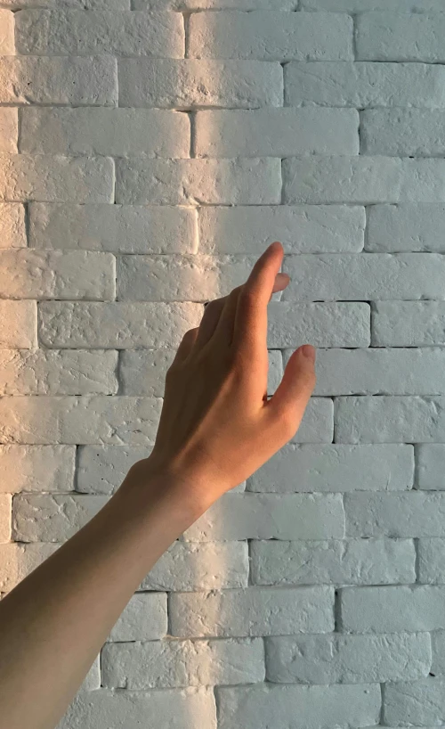 a close up of a person's hand near a brick wall, light and space, light simulation, t-pose, instagram post, low quality photo