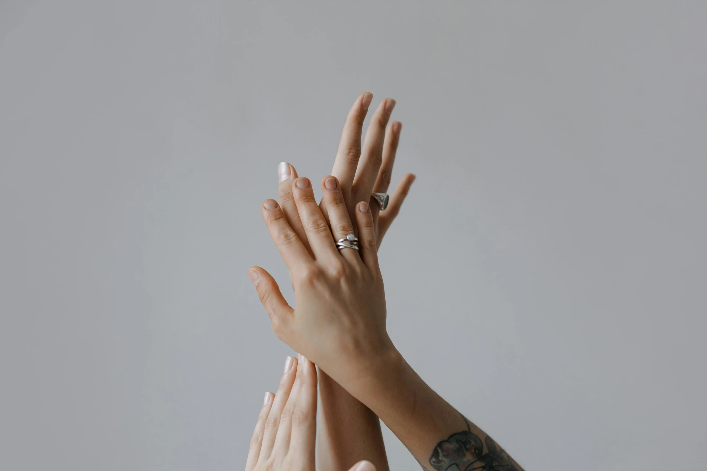 a group of people with their hands in the air, a tattoo, by Matija Jama, trending on pexels, aestheticism, mother of pearl jewelry, on a gray background, background image, nail polish