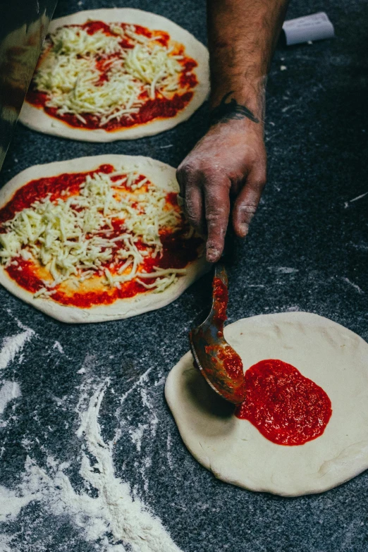 a close up of a person making pizzas on a table, different sizes, intense colours, daily specials, tall
