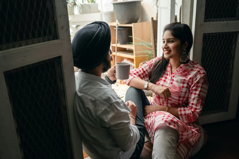 a woman sitting next to a man holding a cup of coffee, inspired by Manjit Bawa, leaning on door, talking, happy friend, connection rituals