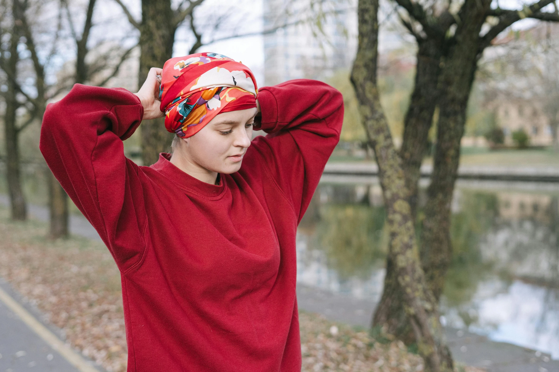 a woman in a red shirt and a red turban, by Emma Andijewska, pexels, happening, wearing sweatshirt, in a park, patterned clothing, marina federovna