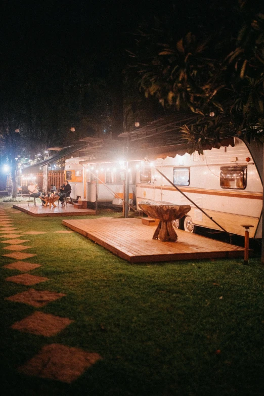 a trailer parked next to a tree at night, a portrait, unsplash, happening, party in jungles, d. i. y. venue, profile image, panoramic shot