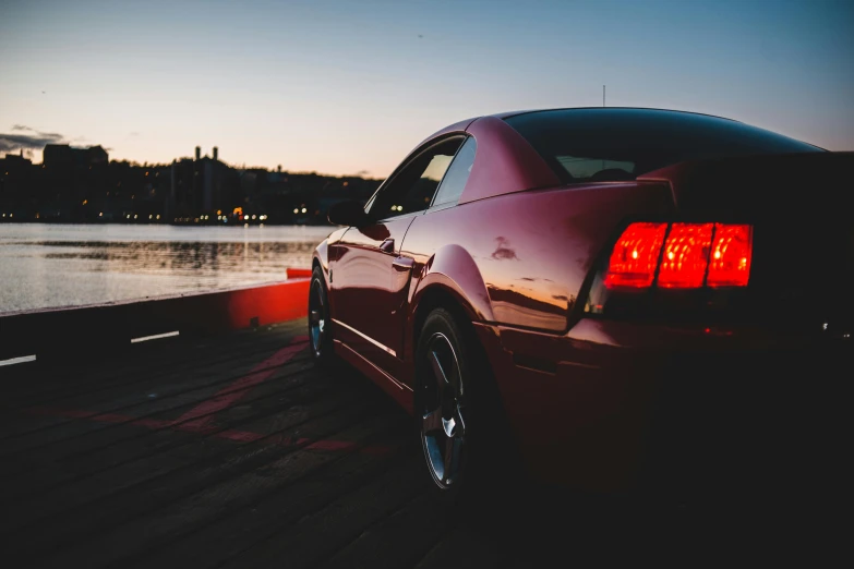 a red car parked next to a body of water, pexels contest winner, romanticism, soft evening lighting, mustang, avatar image, profile view perspective