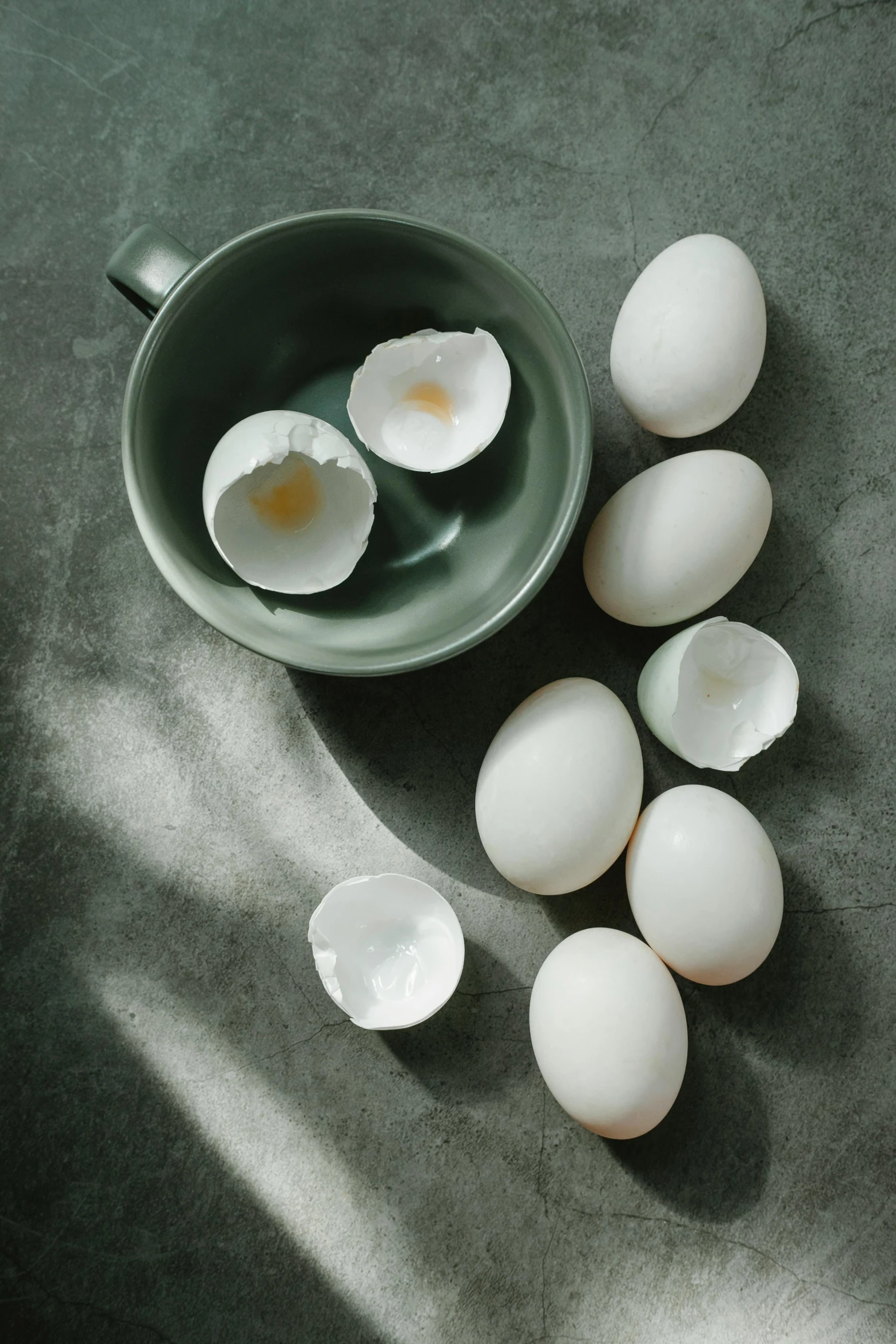 a bowl filled with eggs sitting on top of a table, 王琛, grey