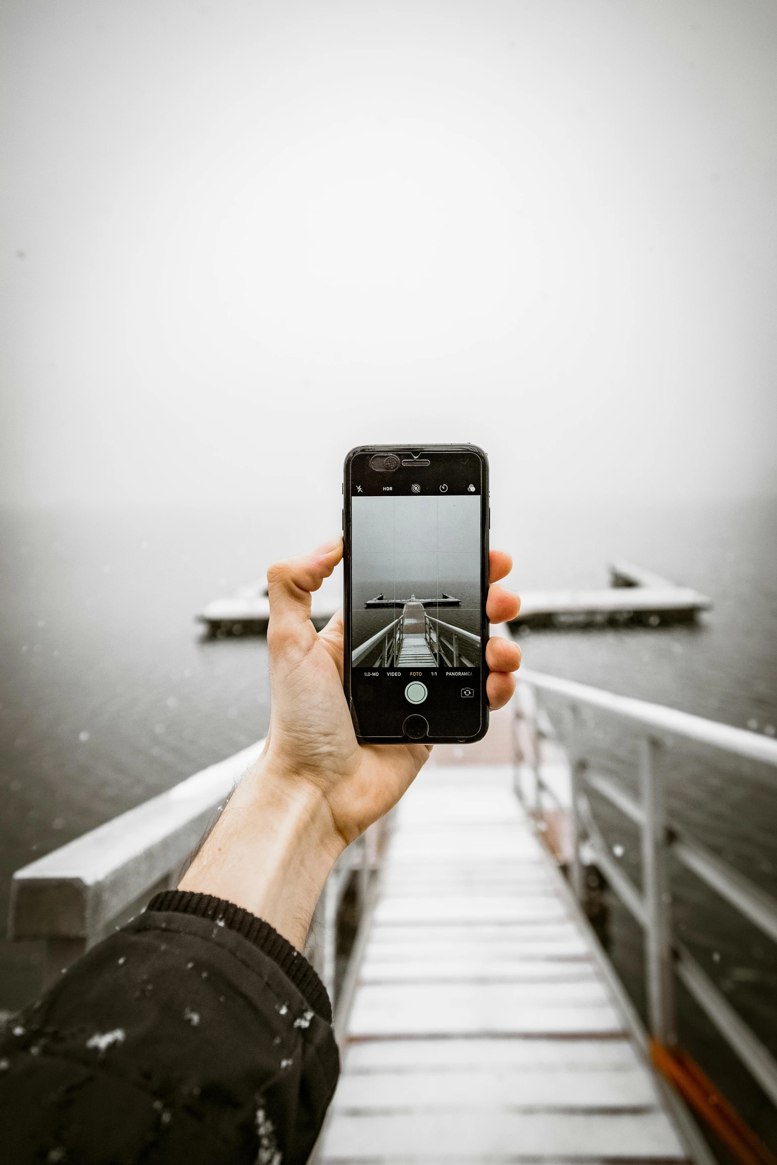 a person taking a picture of a boat in the water, grey, small dock, design, mount