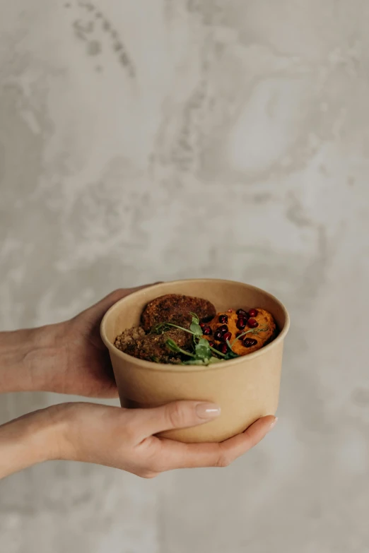 a person holding a bowl with food in it, by Emma Andijewska, cardboard, professional product photo, caramel. rugged, front shot