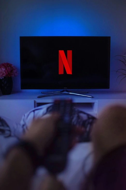 a person laying in bed watching netflix on tv, by Dan Content, pexels, serial art, big glowing netflix logo behind, spring evening, narrow shot, ( ( theatrical ) )